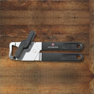 Victorinox manual stainless steel can opener black handle on wooden surface